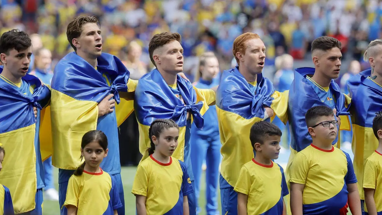 Los jugadores de la selecci&oacute;n ucraniana con la bandera de su pa&iacute;s atada al cuello entonan el himno nacional en su debut en la Eurocopa 2024 contra Ruman&iacute;a. EFE/EPA/RONALD WITTEK